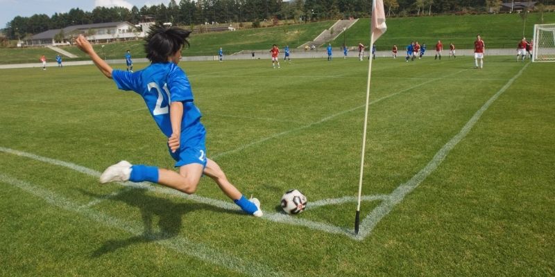 Hình ảnh sân cỏ với cờ góc, nơi các cầu thủ đang chuẩn bị thực hiện cú đá phạt góc